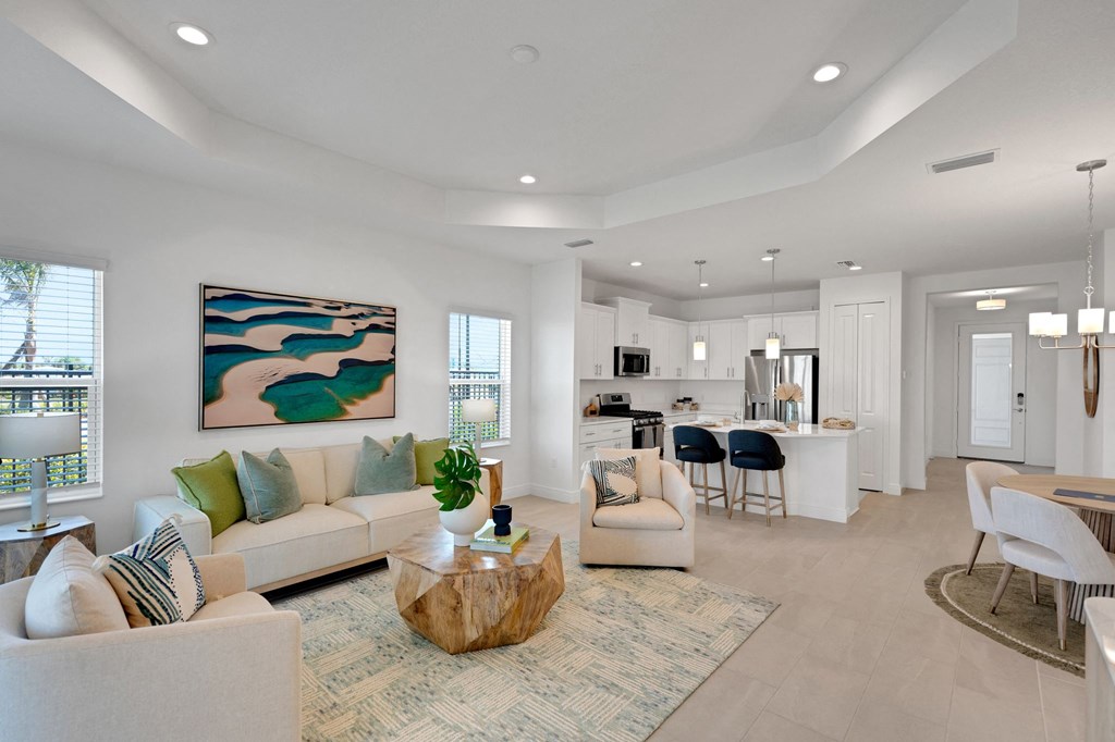 a living room with couches and a coffee table in front of a kitchen