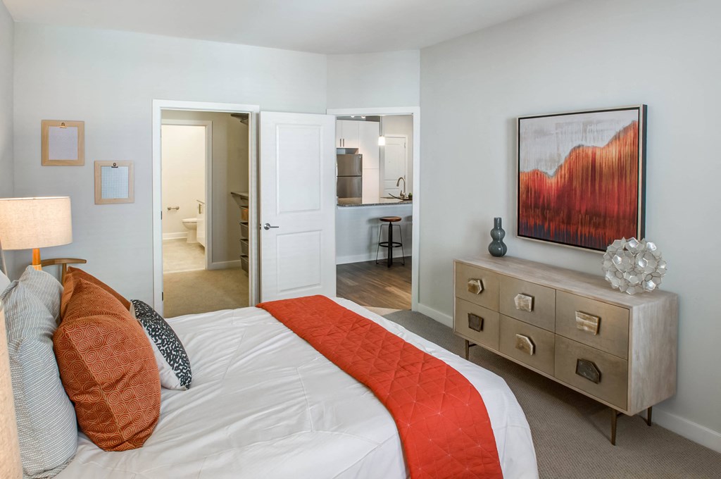 a bedroom with a bed and a dresser and a bathroom