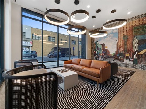 A modern living room with a brown leather couch and a large mural on the wall.