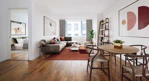 A living room with a grey sofa, a wooden table and chairs, and a red rug.