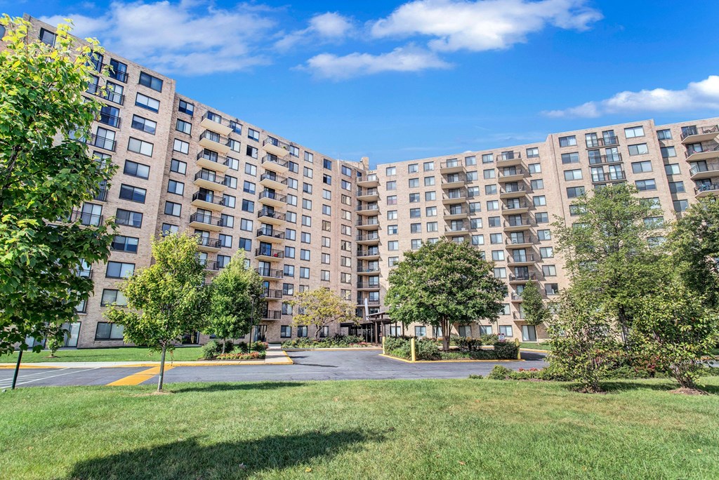 a view of a large apartment complex with grass and trees