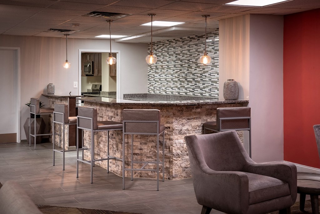 a lobby with chairs and a bar with a stone wall