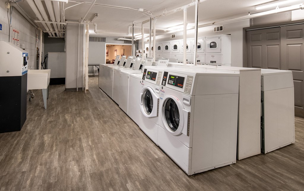 a row of white washers and dryers in a laundry room