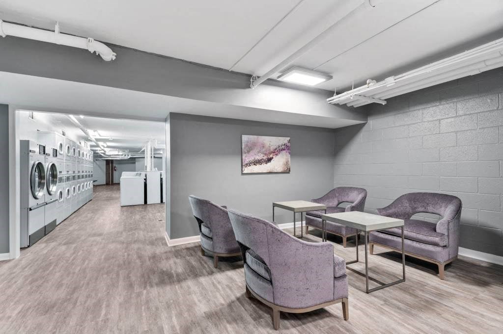 a laundry room with purple chairs and tables and a washing machine