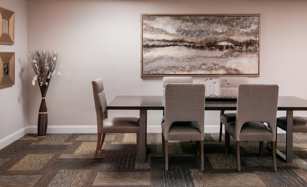 a dining room with a table and chairs and a painting on the wall