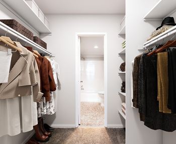 a walk in closet filled with clothes and a door to a bathroom