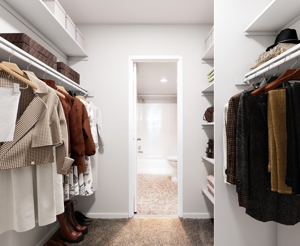 a walk in closet filled with clothes and a door to a bathroom