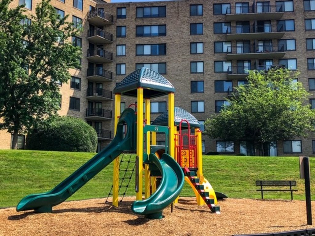 a playground with slides in front of an apartment building