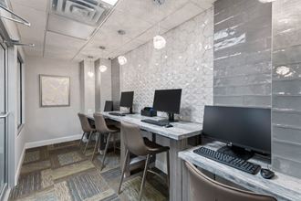 a computer room with desks and chairs and a monitor