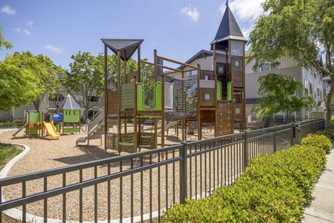 A playground with a wooden swing set and a green slide.