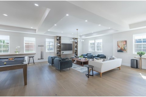 A spacious living room with a pool table and a couch.
