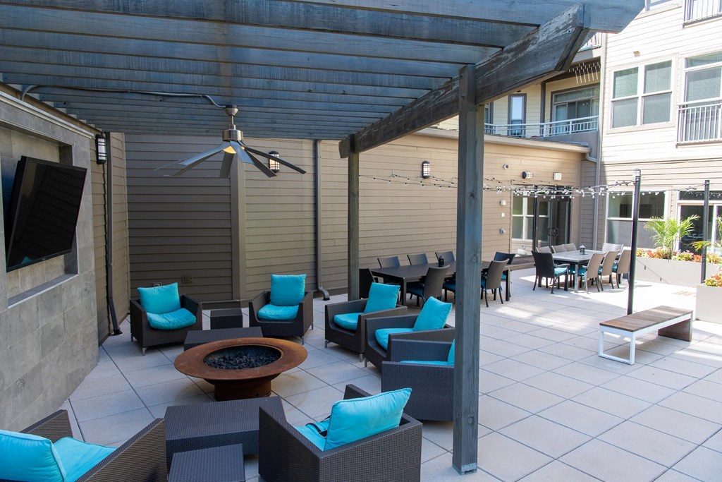 a covered patio with blue chairs and a fire pit