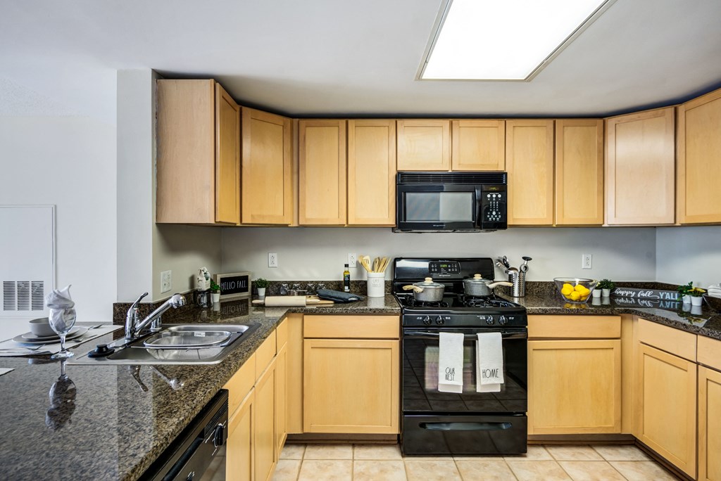 a kitchen with wood cabinets and black appliances and granite counter tops