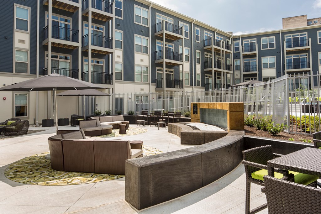 a courtyard with furniture and a fire pit in front of an apartment building