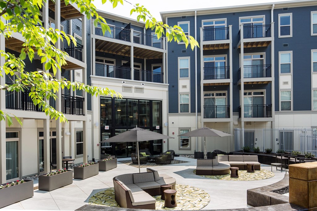 a courtyard with couches and umbrellas in front of an apartment building