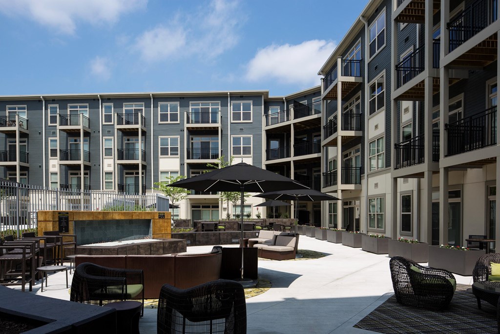 a courtyard with tables and chairs and an umbrella in front of an apartment building