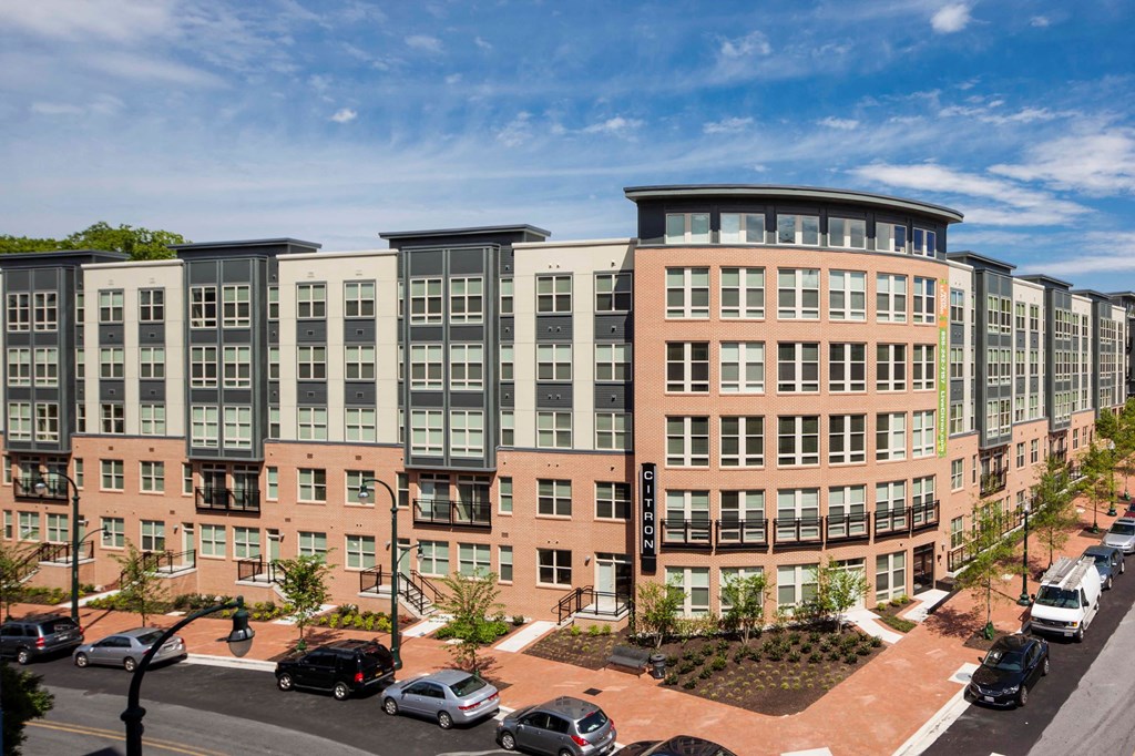 an exterior view of an apartment building with cars parked in front of it