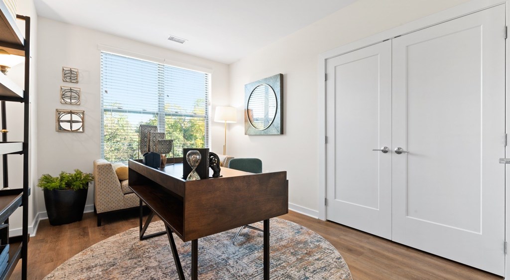 A room with a wooden table and chairs, a mirror, and a window with a view of the outdoors.