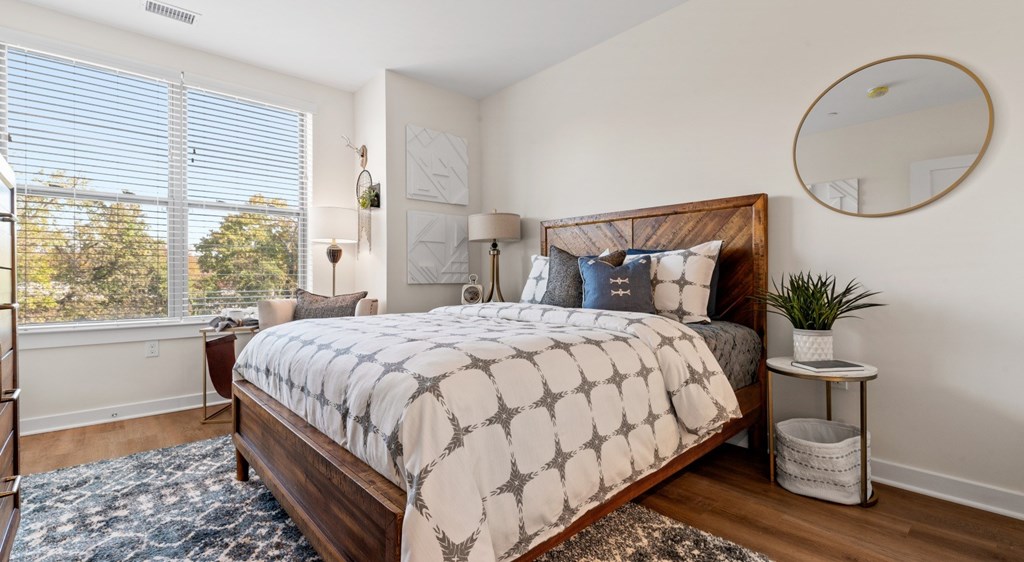 A bedroom with a large bed and a window with blinds.