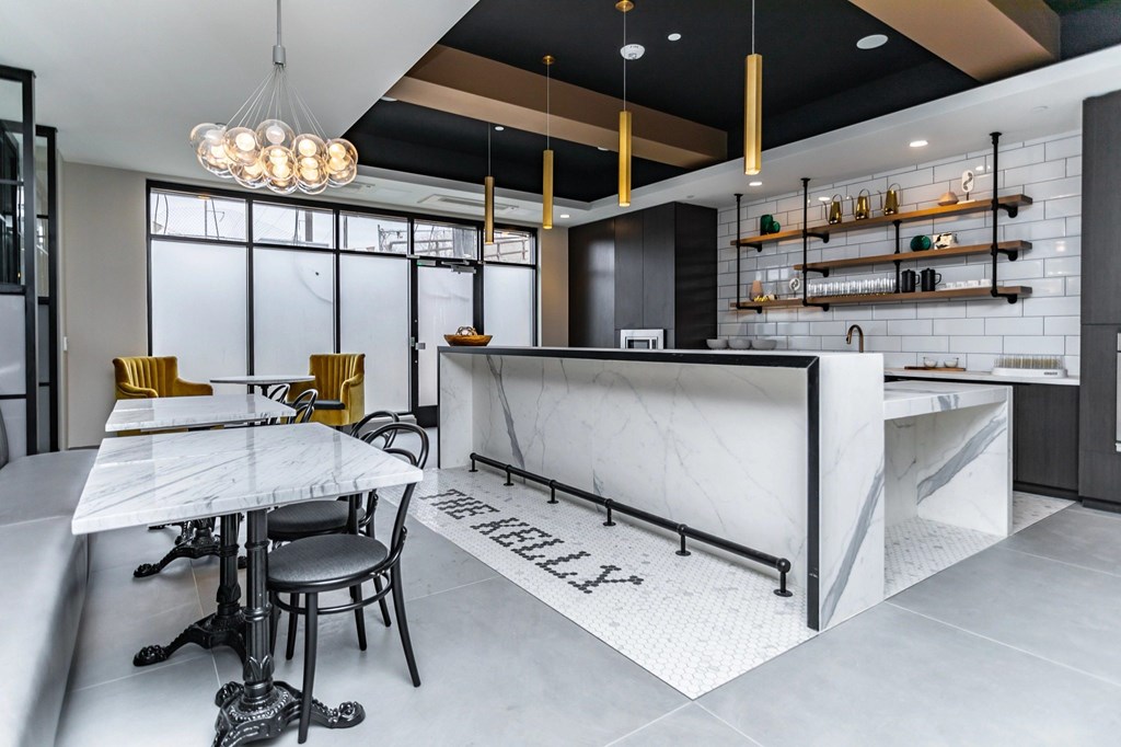 A modern kitchen with a marble island and bar stools.