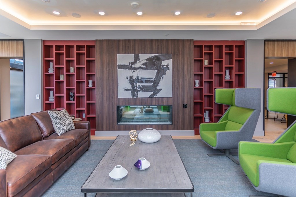 A living room with a brown leather couch, a grey armchair, a coffee table, and a large painting on the wall.