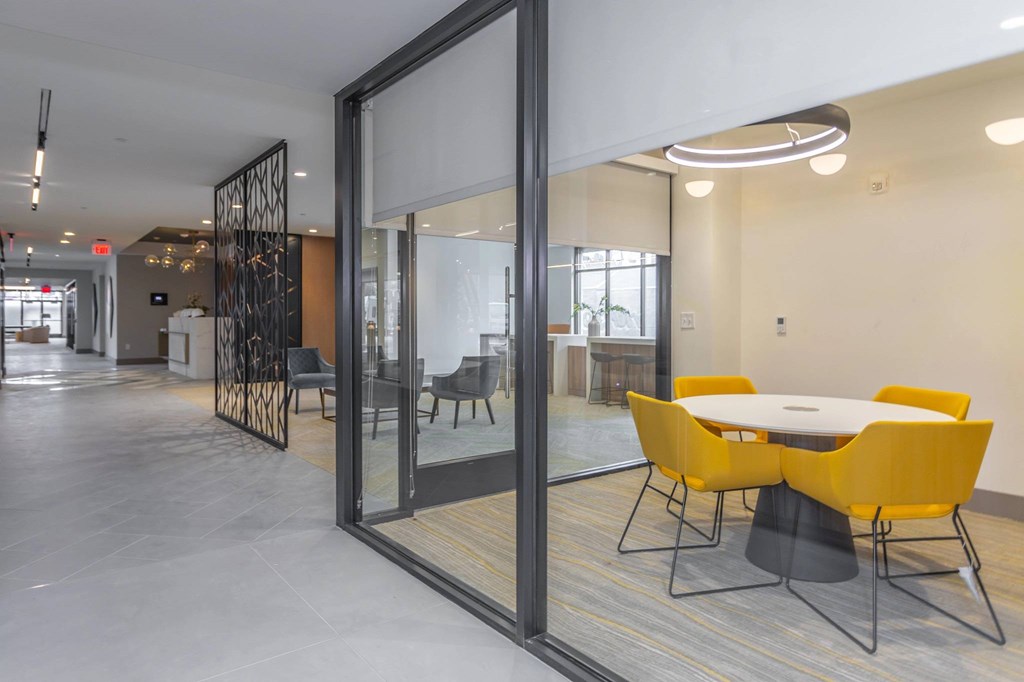 A conference room with a glass door and a table with yellow chairs.