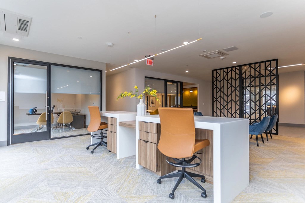 A modern office space with a white desk and orange chairs.