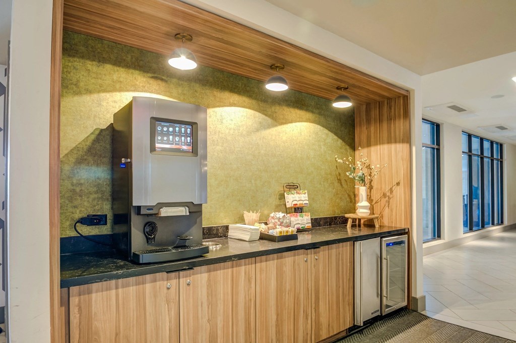 A coffee machine is on a counter with a digital menu board above it.
