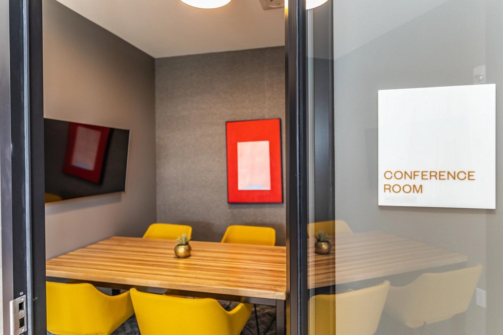 A conference room with a wooden table and yellow chairs.