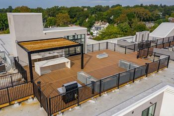 A rooftop patio with a grill and seating area.