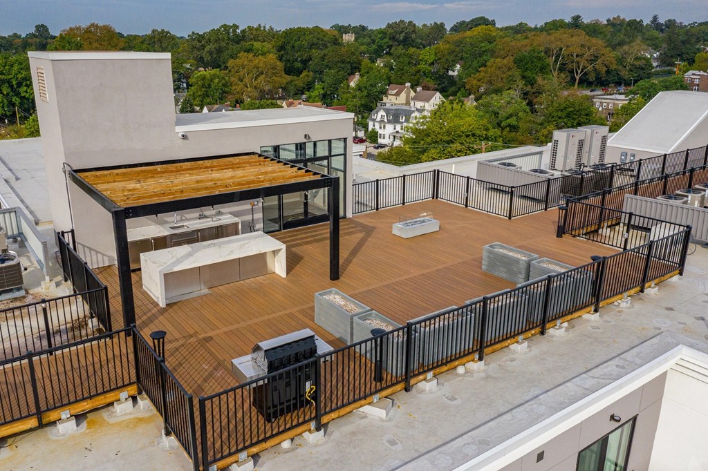 A rooftop patio with a grill and seating area.