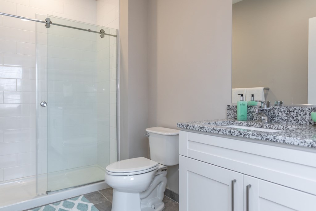 A white toilet sits next to a glass shower door in a bathroom.