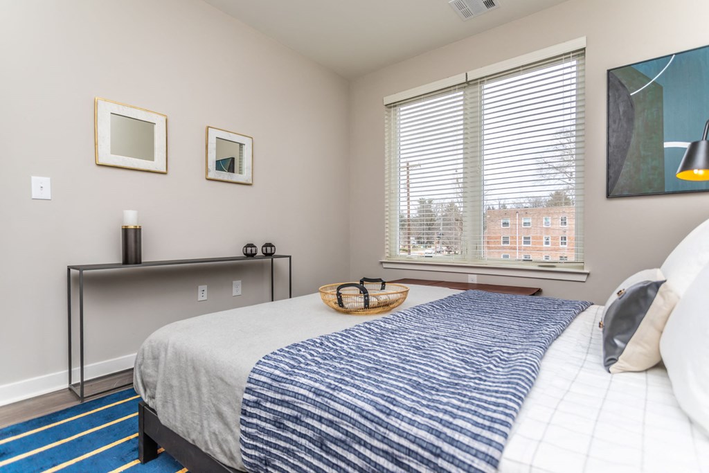 A bedroom with a bed, a table with candles, and a window with blinds.