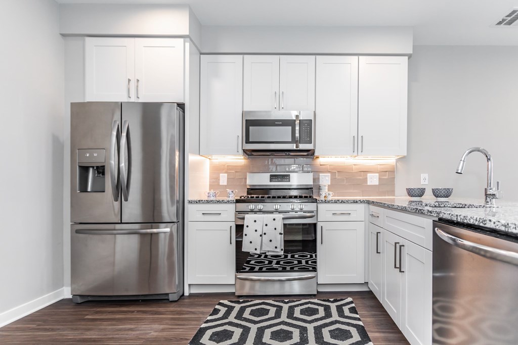 A modern kitchen with a stainless steel refrigerator and white cabinets.