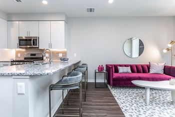 A modern kitchen with a pink couch and a marble countertop.