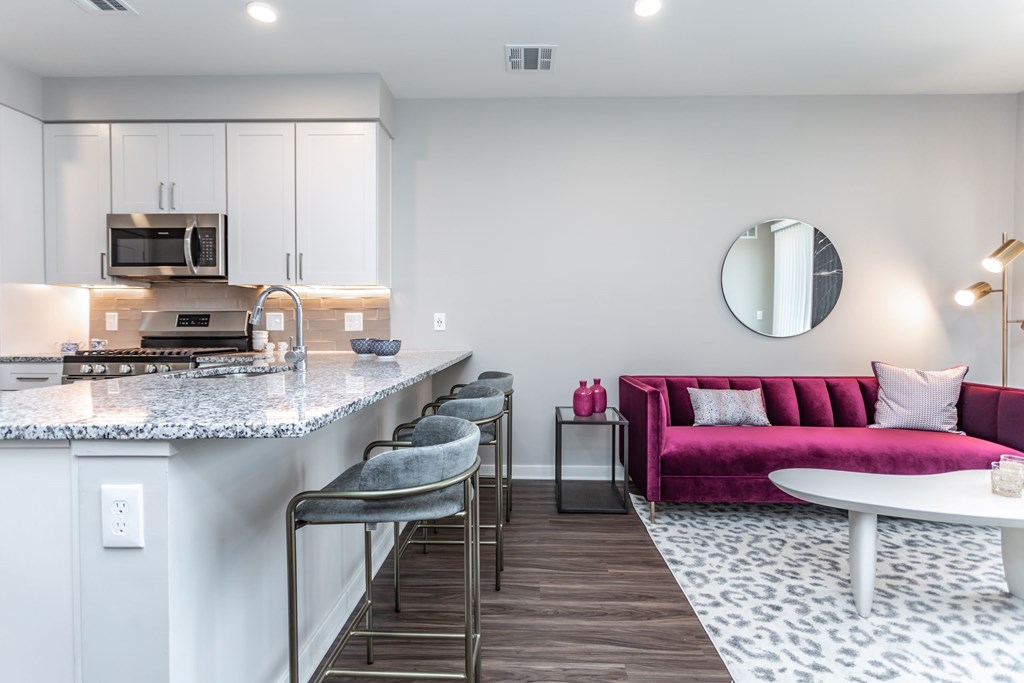 A modern kitchen with a pink couch and a marble countertop.