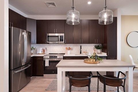 A modern kitchen with a white table and brown chairs.