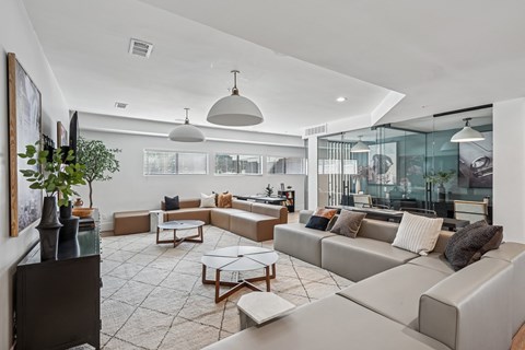 A modern living room with a grey sofa set and a glass table.