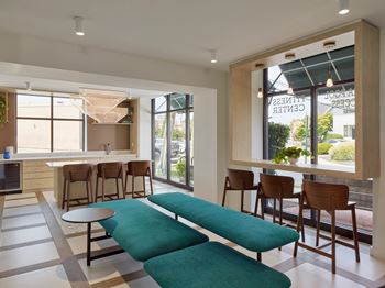 A modern living room with a green sofa and wooden chairs.