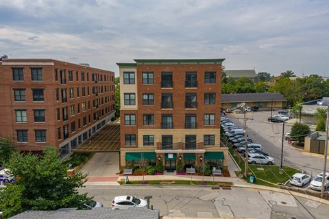 A parking lot is in front of a building with a green awning.