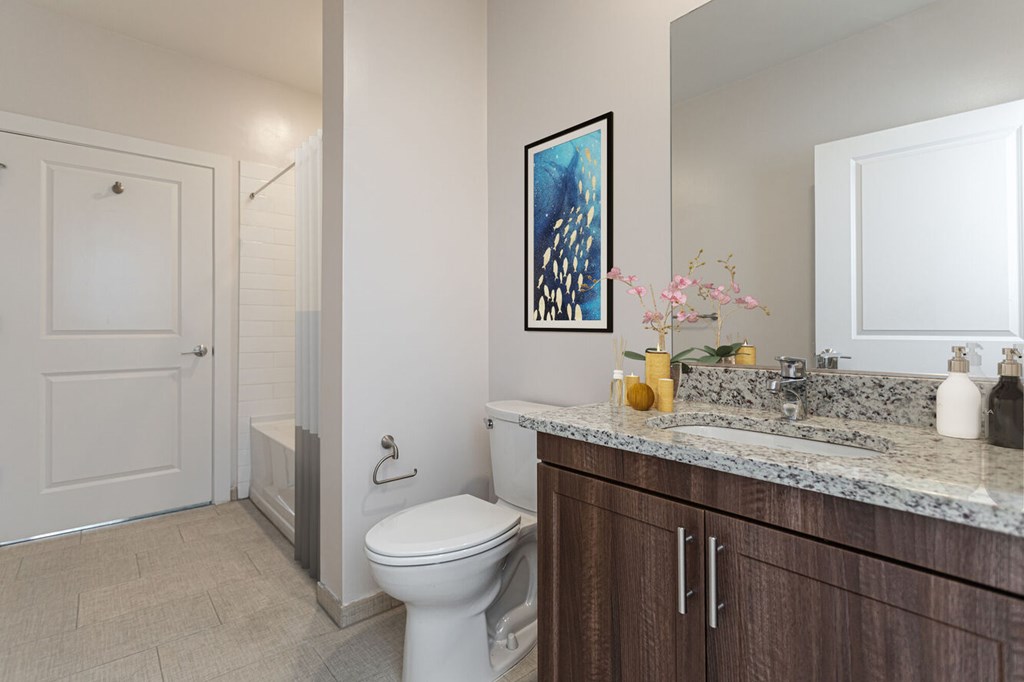A bathroom with a toilet, sink, and a painting on the wall.