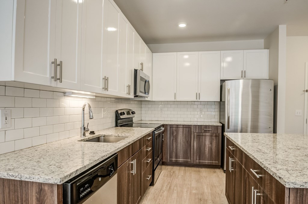 A kitchen with white cabinets and a granite countertop.