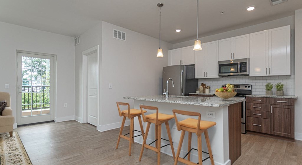 A kitchen with white cabinets and a bar area with stools.