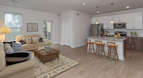 A well-lit, modern kitchen with a breakfast bar and a living room area with a sofa and coffee table.