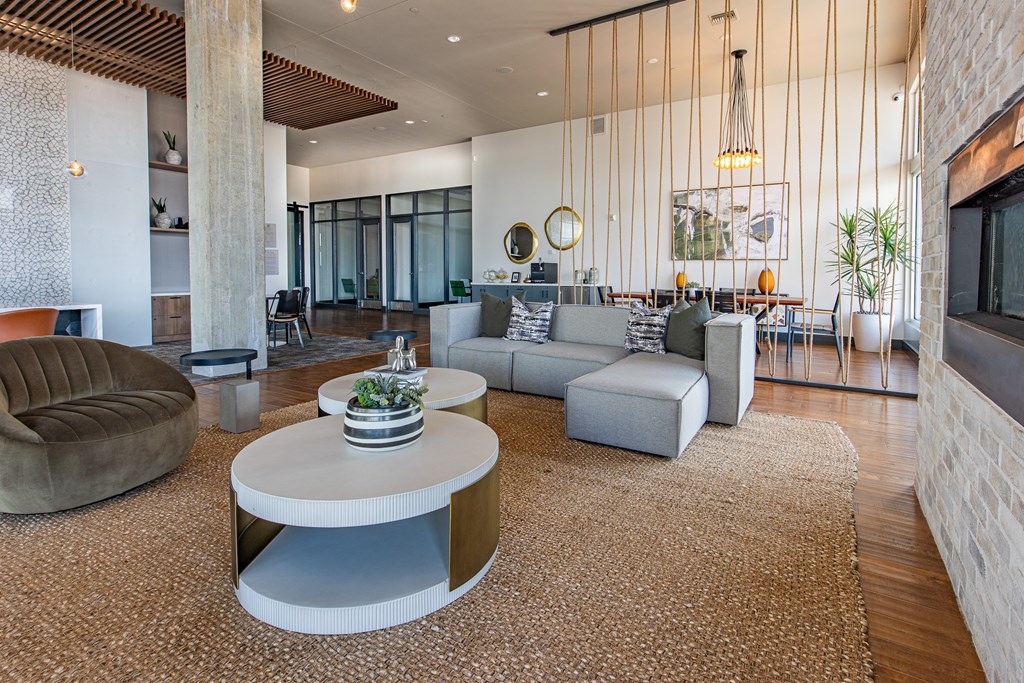 A modern living room with a large grey sofa, a round armchair, and a coffee table with a bowl of fruit on top.