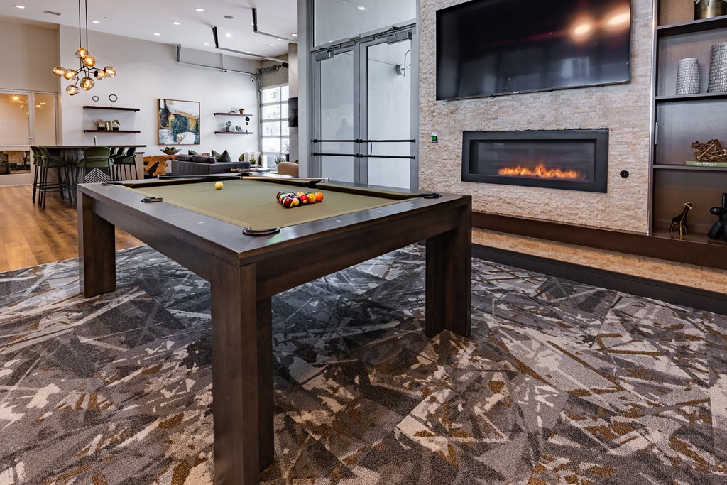 A pool table in a room with a fireplace and a television.