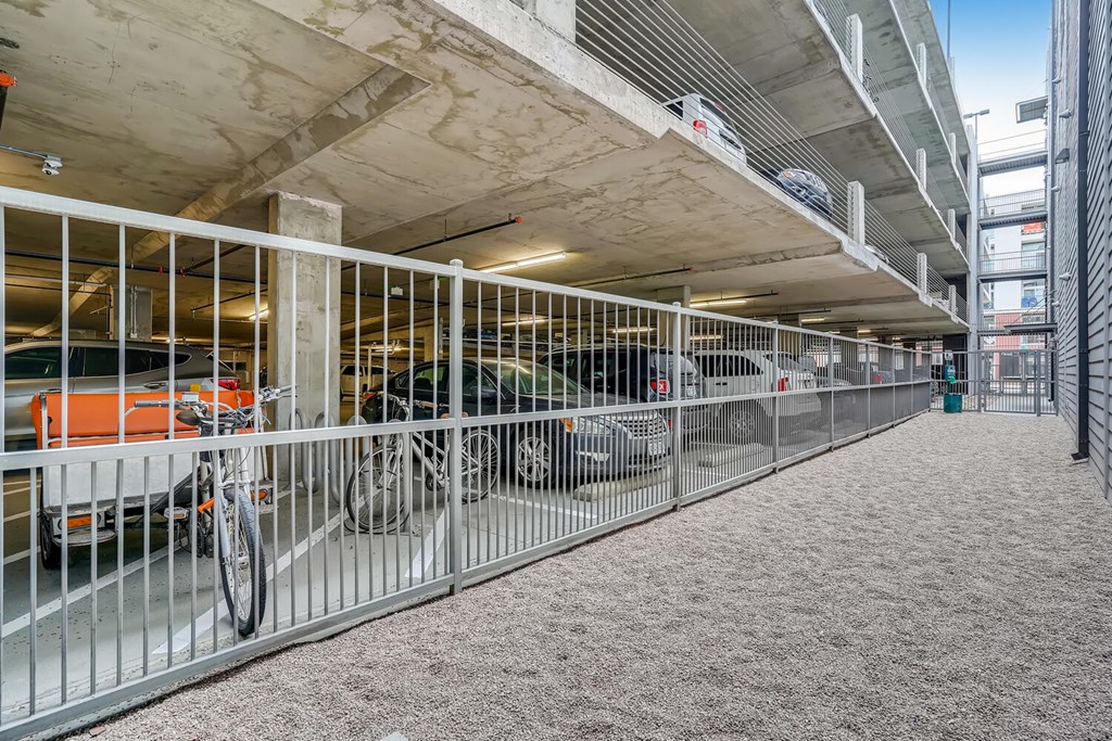 A parking garage with a bicycle and cars parked.