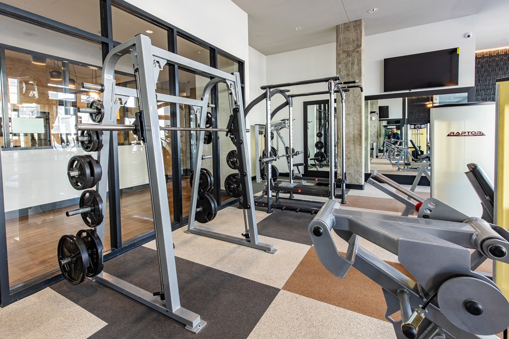 A gym with a squat rack and a mirror.