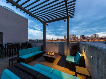 A patio with a fire pit and seating area overlooking a city skyline.