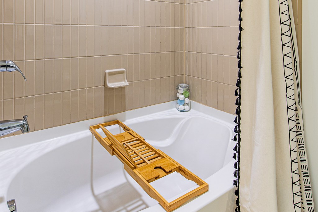 A white bathtub with a wooden tray in the middle.